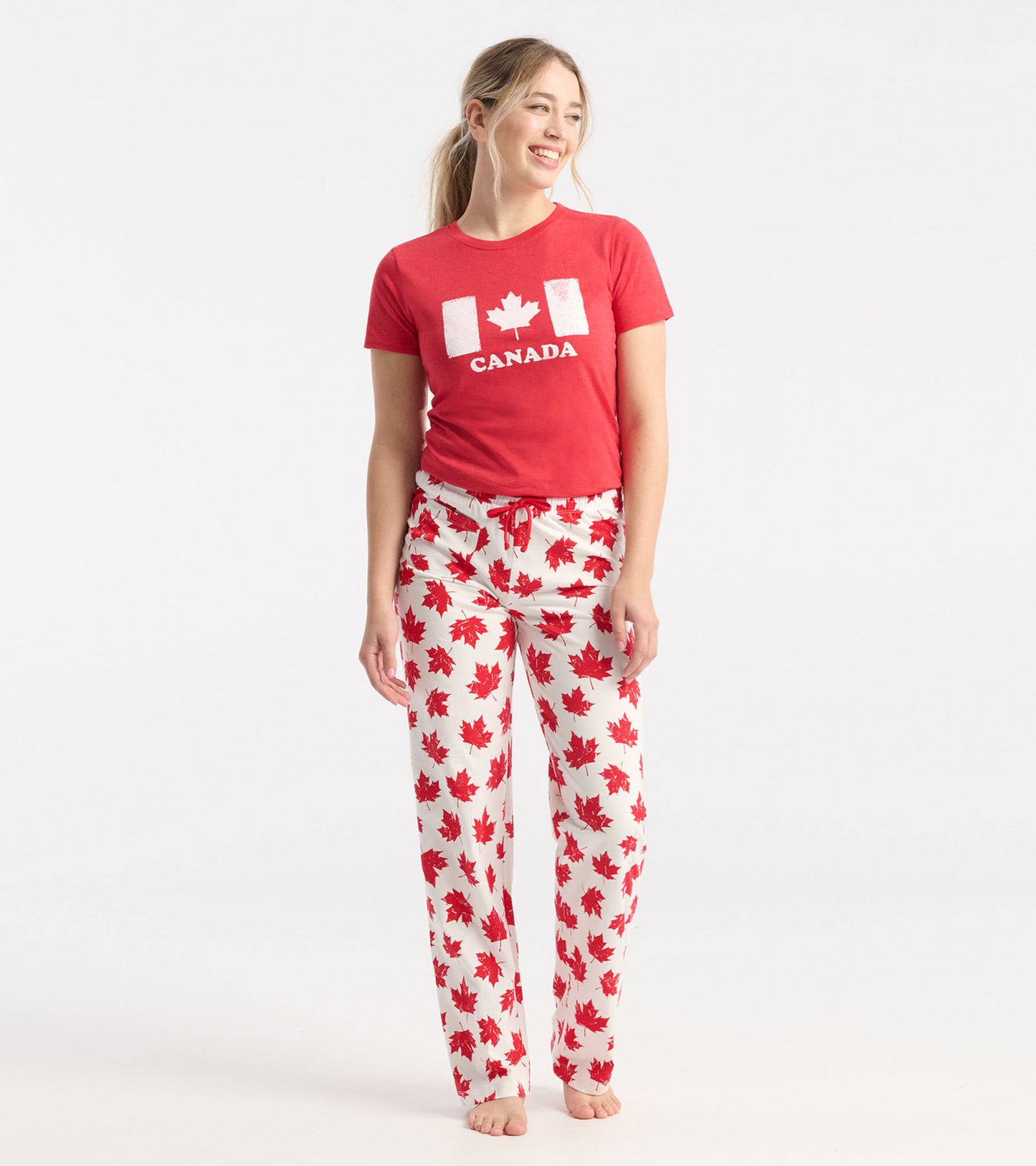 White cotton pajama pants with a red maple leaf pattern, featuring an elastic waistband and drawstring.