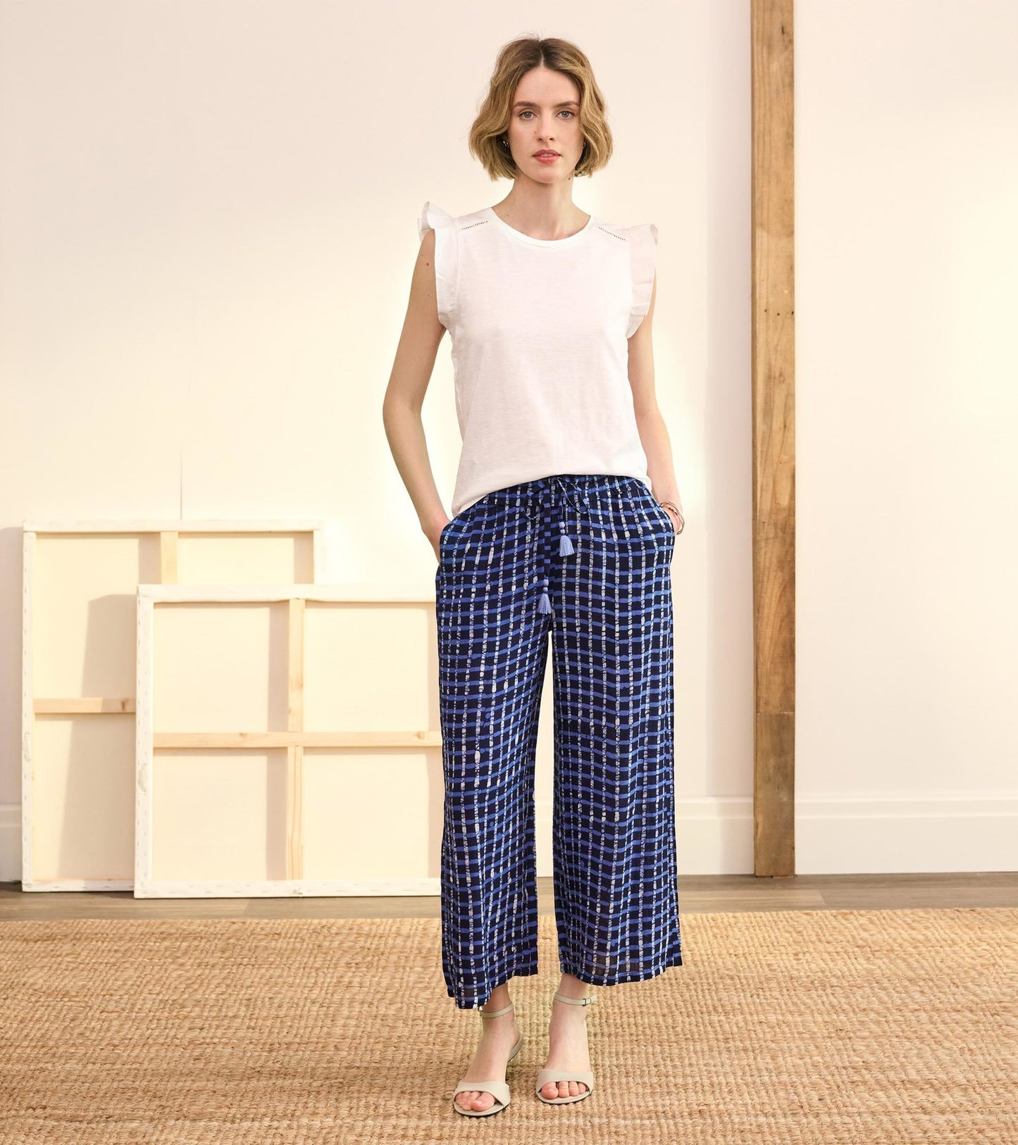 Navy plaid wide-leg pants with a drawstring waist and pockets, styled with a white top and sandals.