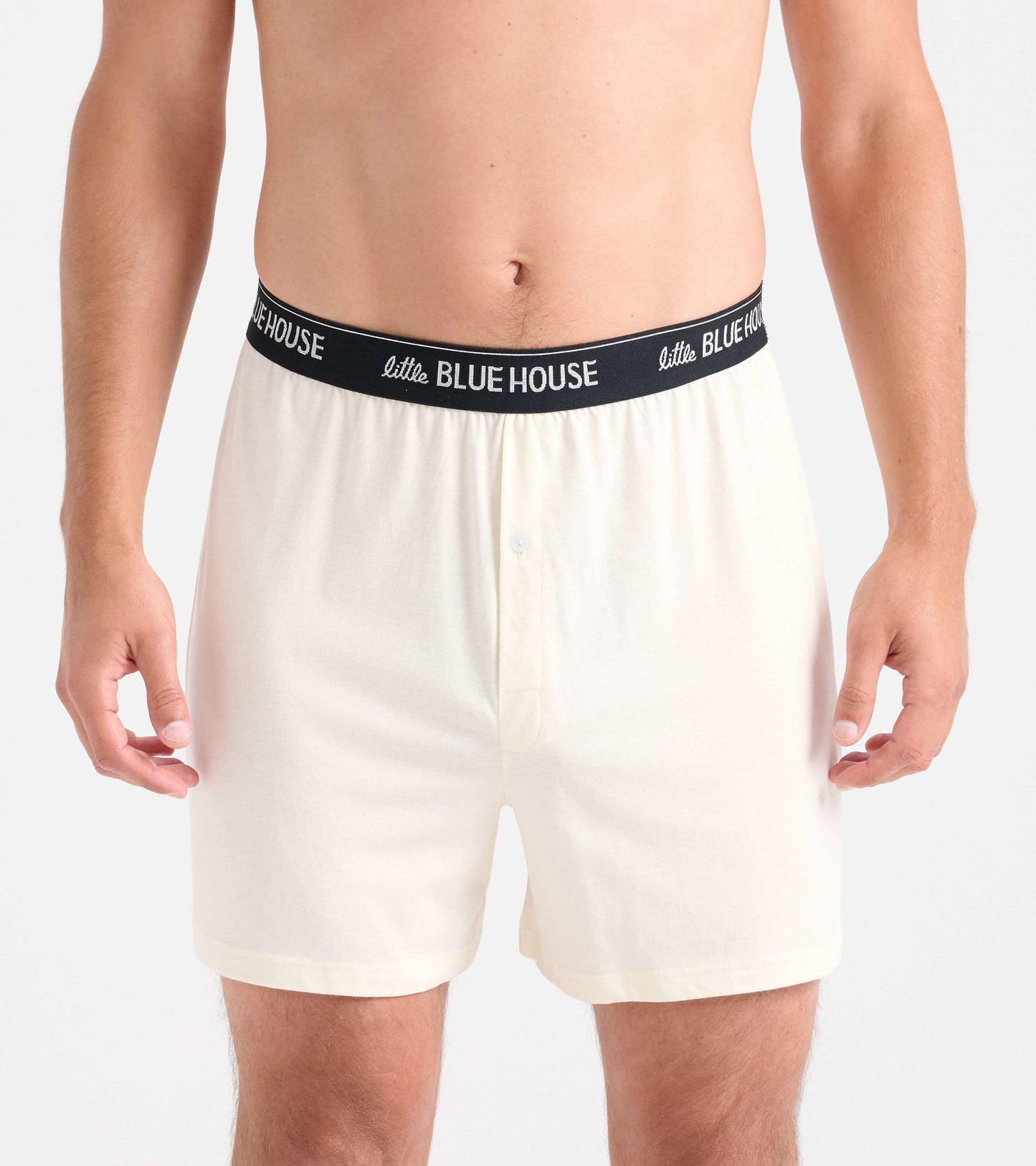 Men's boxer shorts in cream color with a black waistband, featuring a button fly and a relaxed fit.