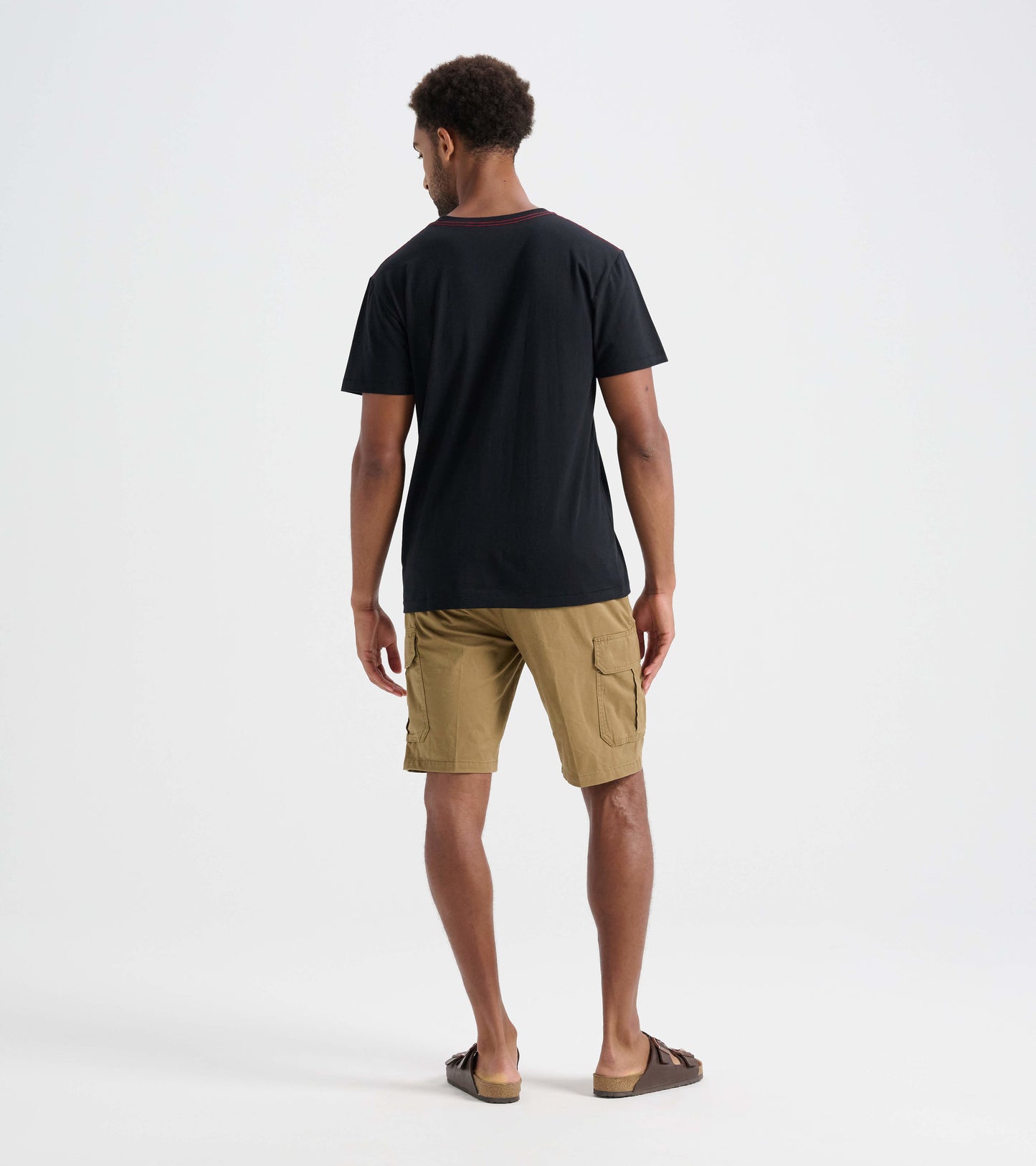 Black men's tee with a round neckline, worn with khaki shorts, shown from the back.