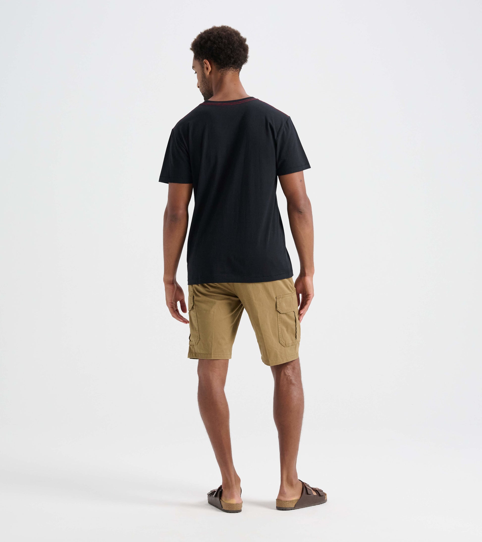 Black men's tee with a round neckline, worn with khaki shorts, shown from the back.