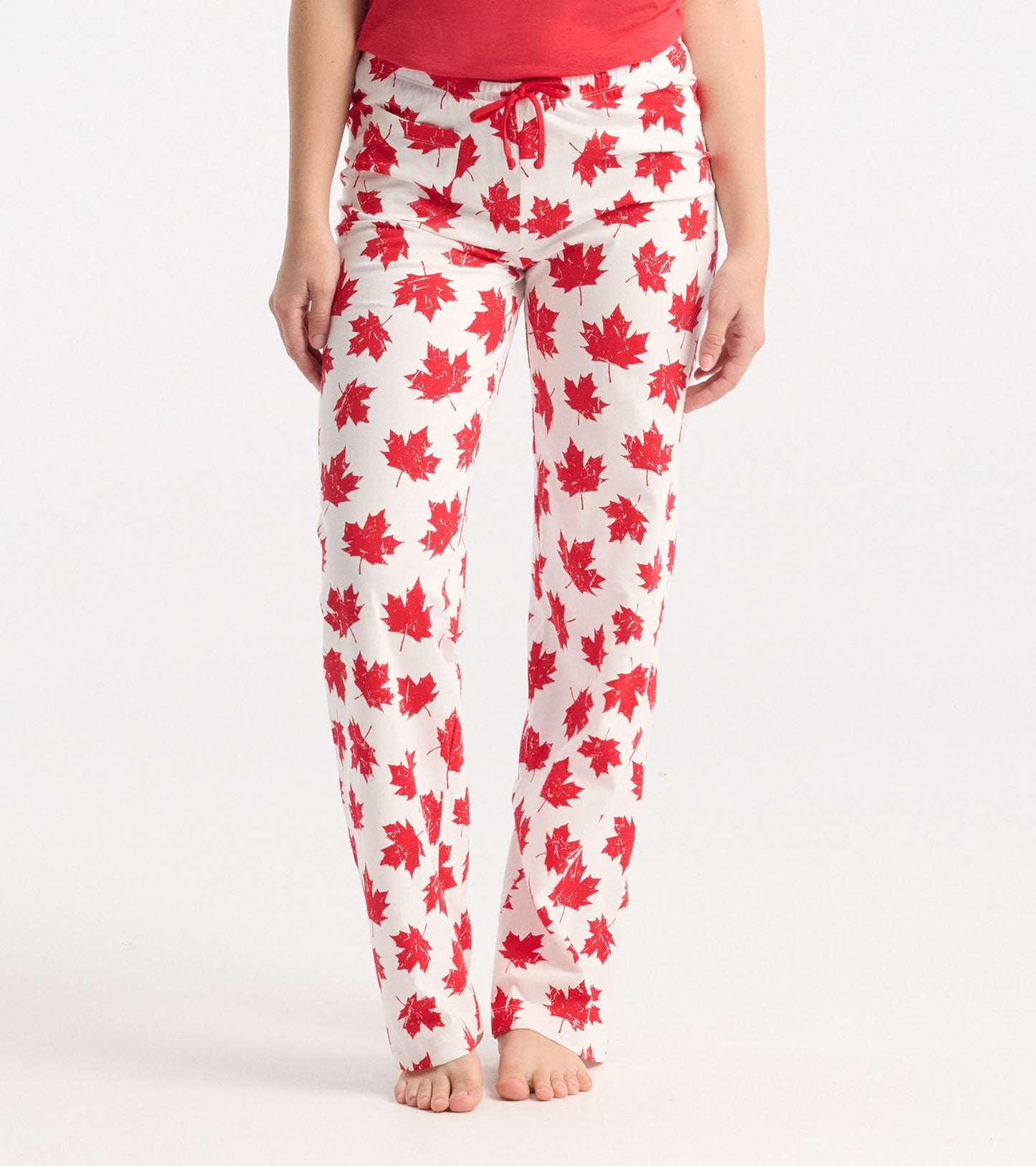 White cotton pajama pants featuring a red maple leaf pattern, with an elastic waistband and drawstring.