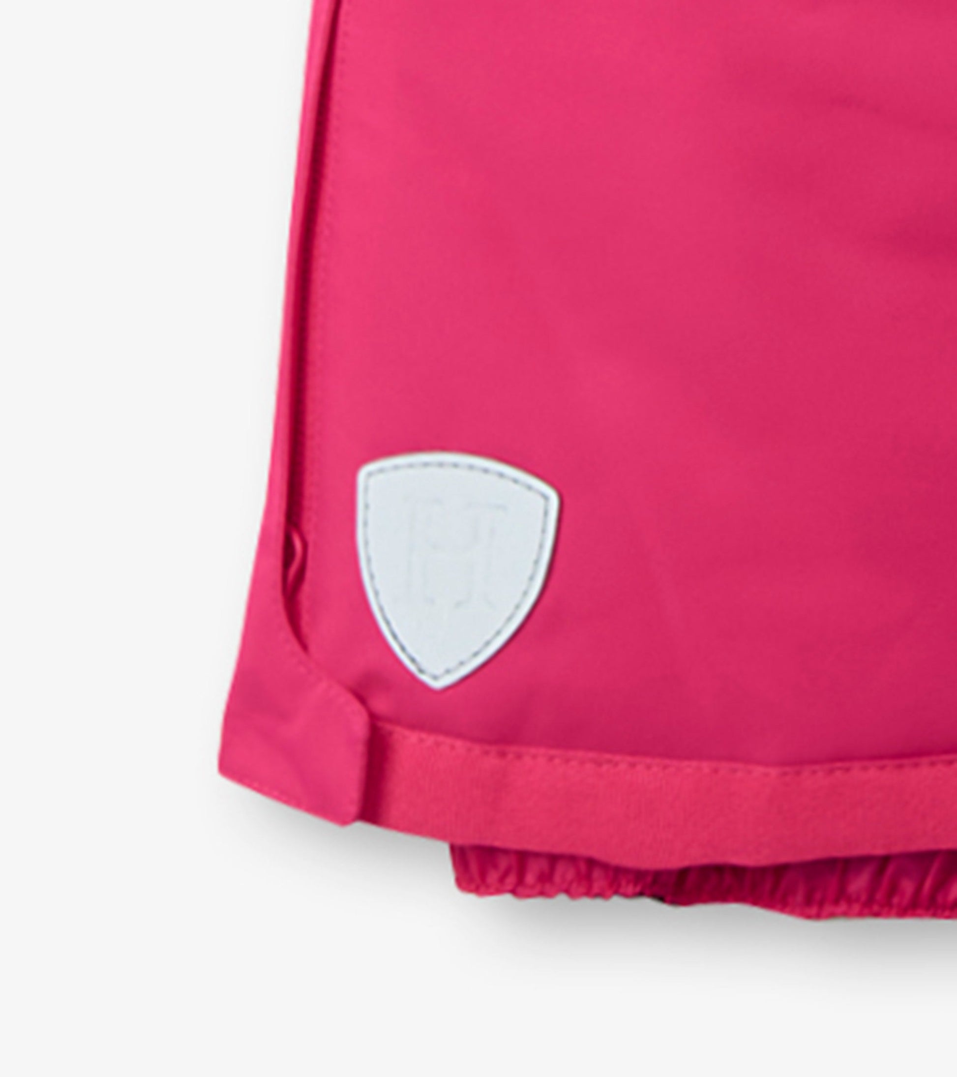 Bright pink kids' snow pants with elastic cuffs and a white logo patch on the side. Ideal for winter activities.