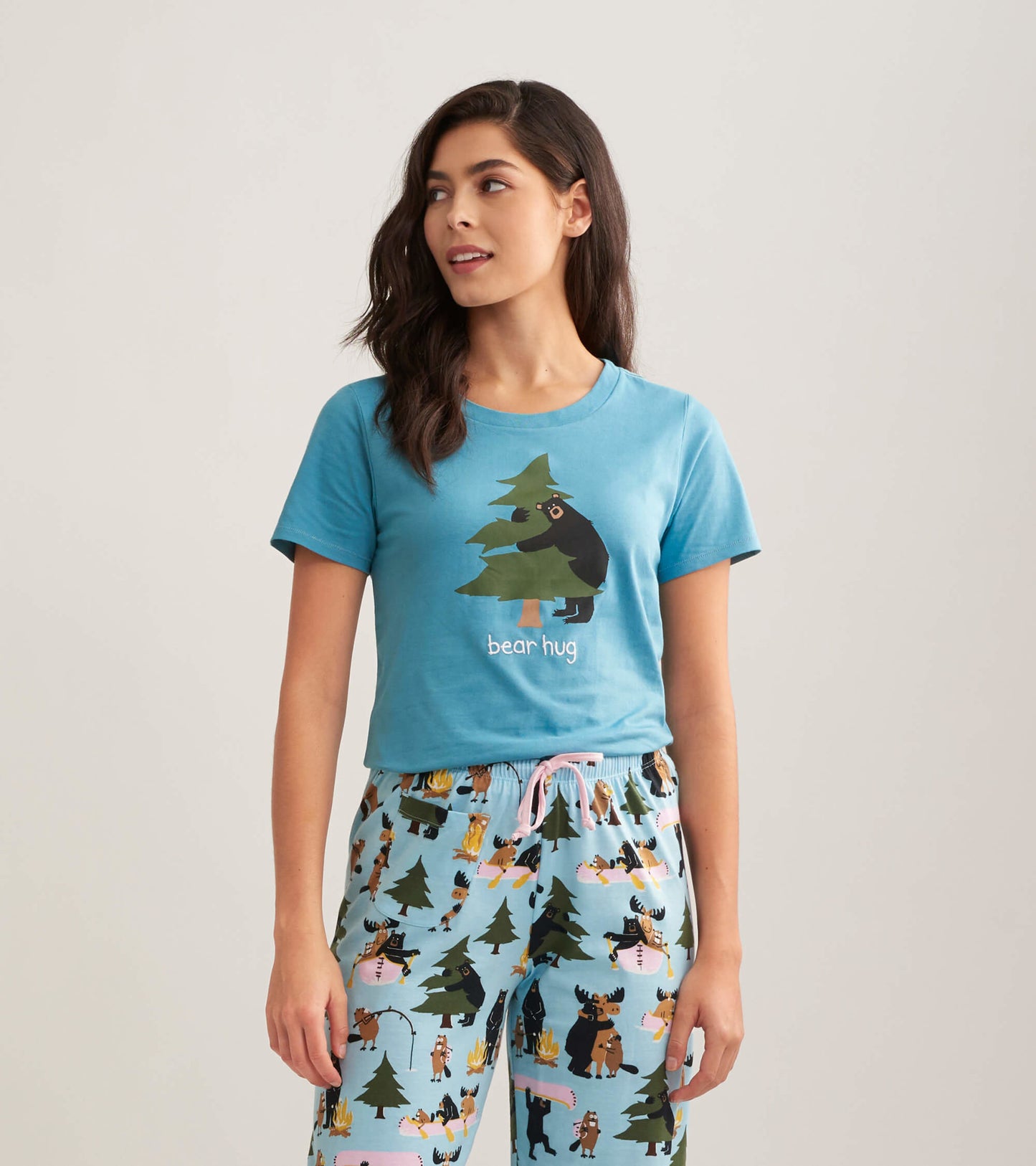 Light blue short-sleeve pajama t-shirt featuring a bear hugging a tree graphic, paired with patterned pajama pants.