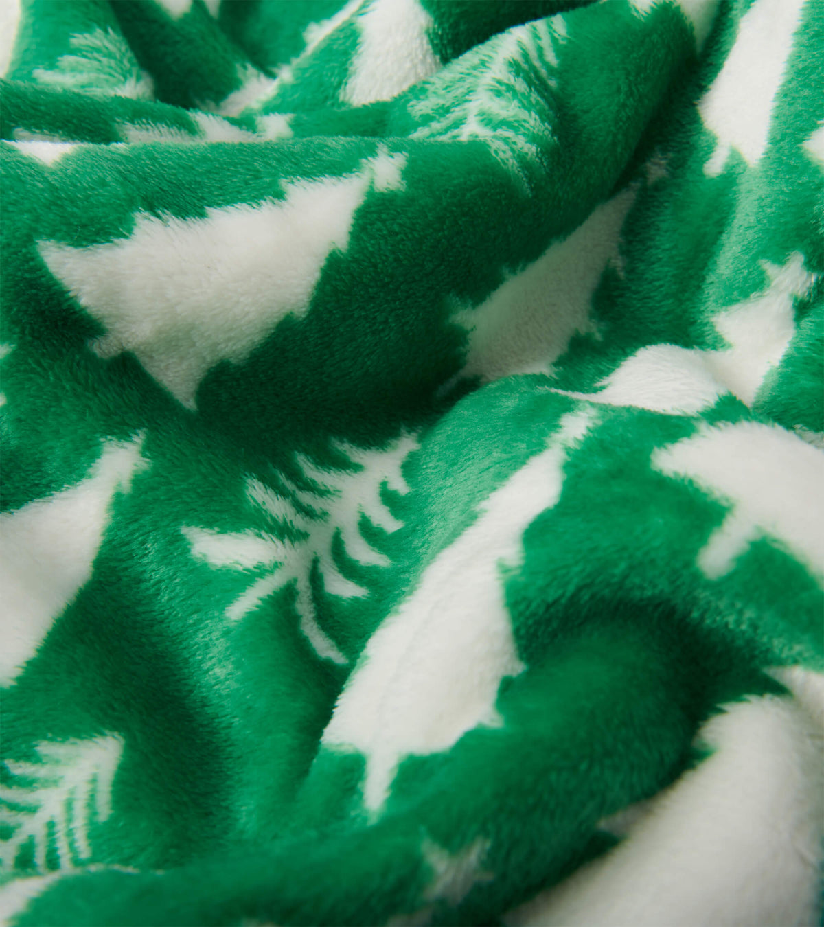 Close-up of green fuzzy fleece blanket with white Christmas tree pattern