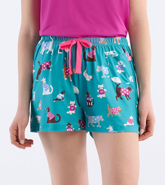 Close-up of teal pajama shorts with cat print, pink drawstring waist, and front patch pocket