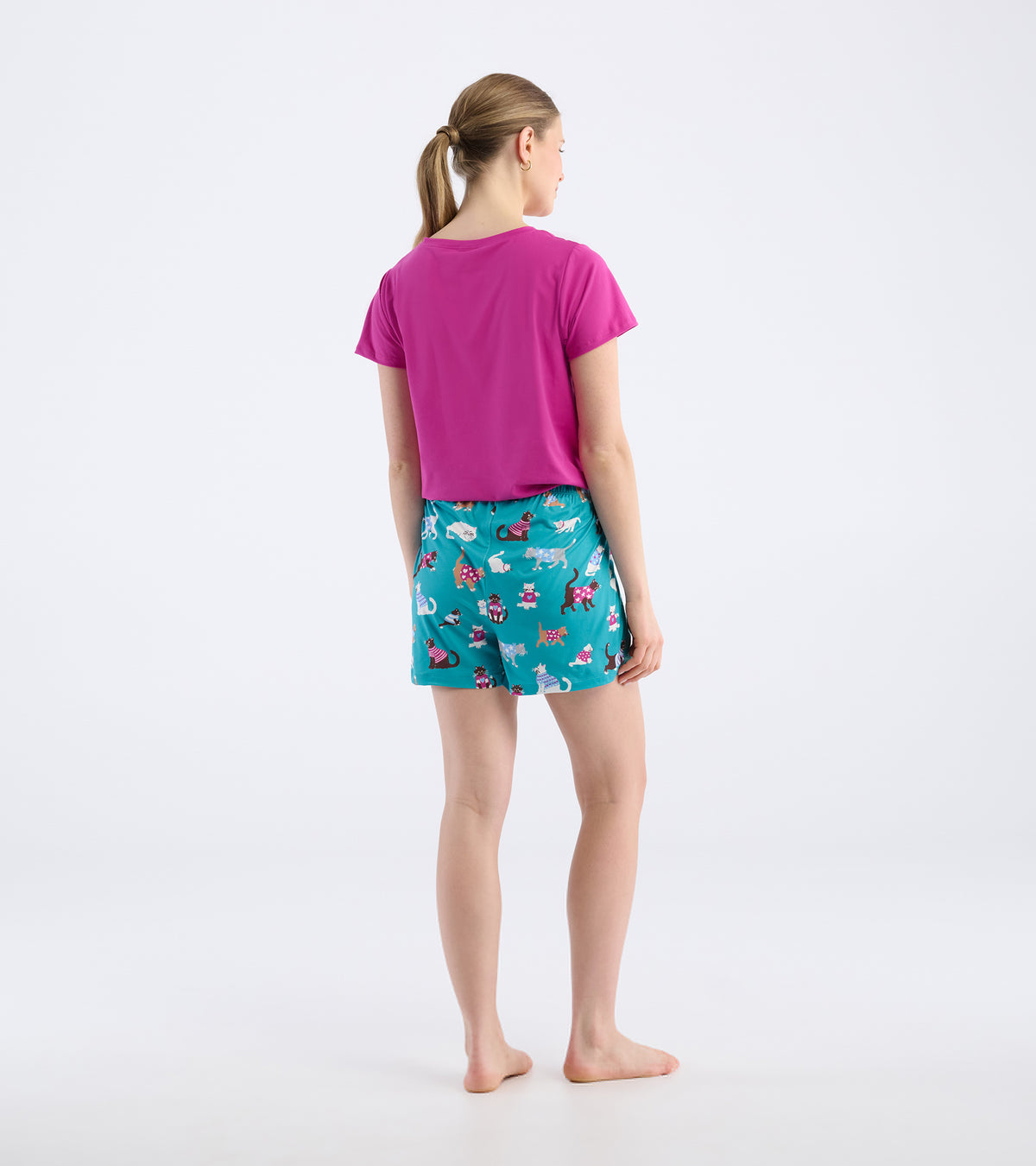 Back view of teal pajama shorts with a colorful cat print on a model