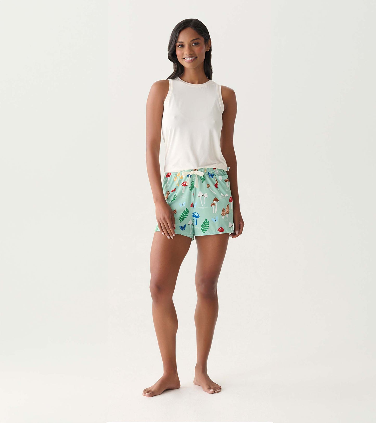 Mint green pajama shorts with colorful mushroom print, shown on a model with a white tank top.