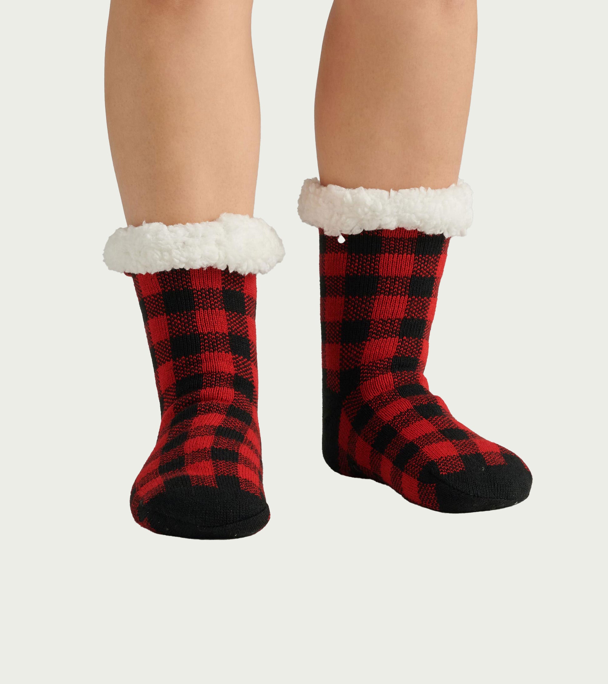Red and black buffalo plaid sherpa-lined cabin socks with white fluffy cuffs, shown on feet
