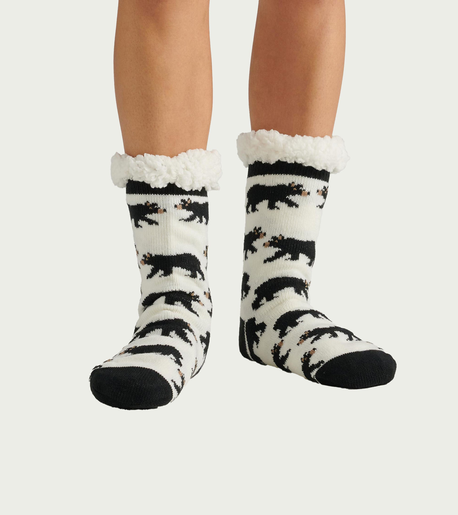 Black and white cabin socks featuring a bear pattern and a soft, fluffy Sherpa lining at the cuff. One size fits all.