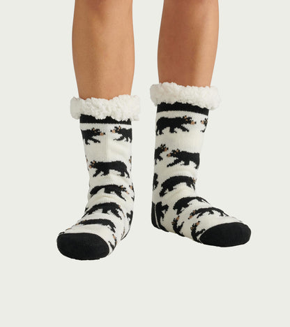 Black and white cabin socks featuring a bear pattern and a soft, fluffy Sherpa lining at the cuff. One size fits all.