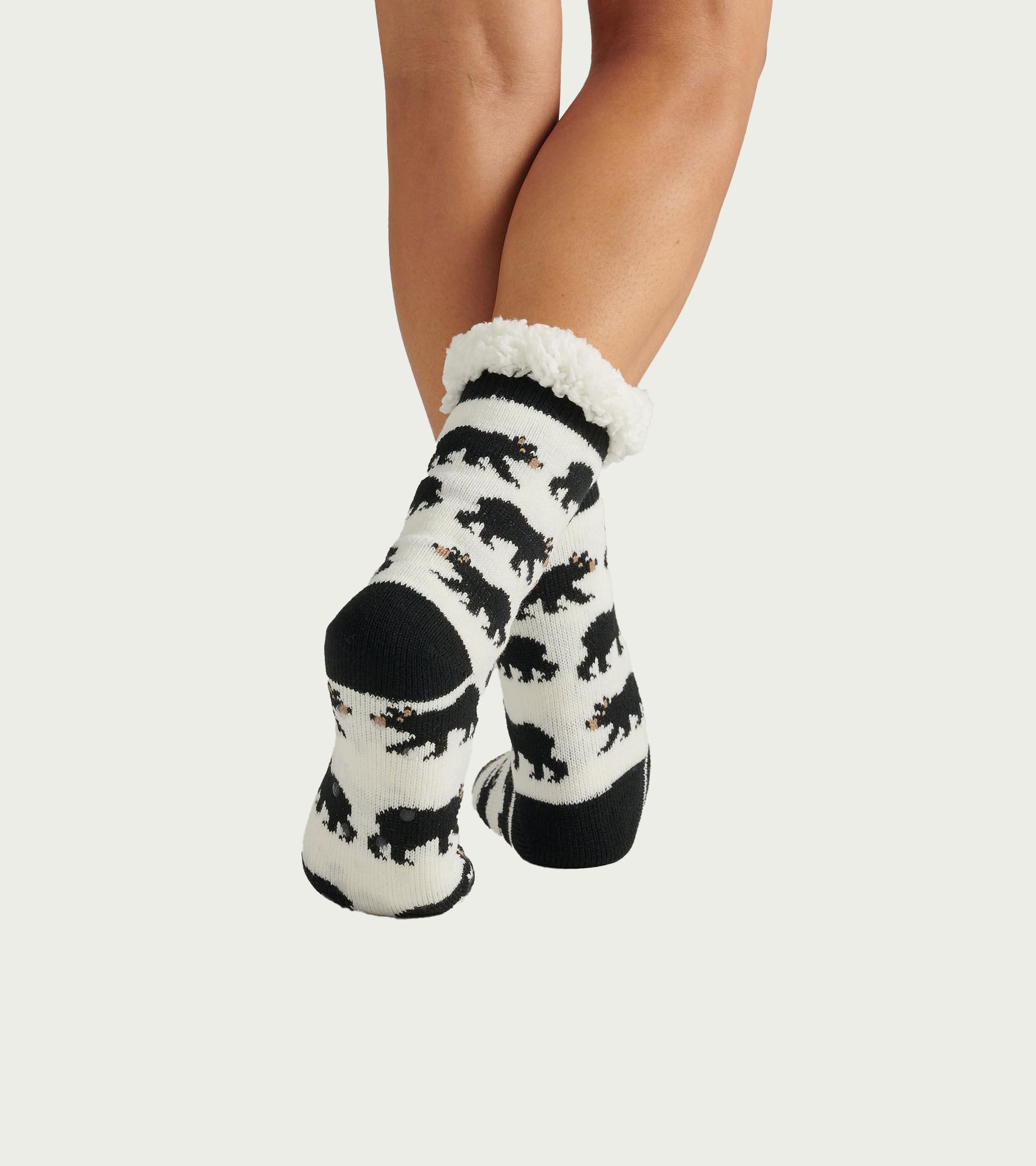 Black and white cabin socks featuring a bear pattern and a cozy Sherpa lining at the cuff. One size fits most.