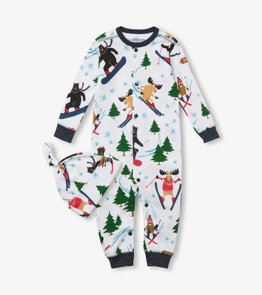 Front of baby sleeper and knot hat set with skiing animal and evergreen print on white