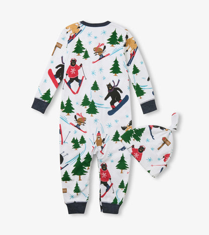 Back of baby sleeper and side of knot hat with skiing animal and evergreen print on white