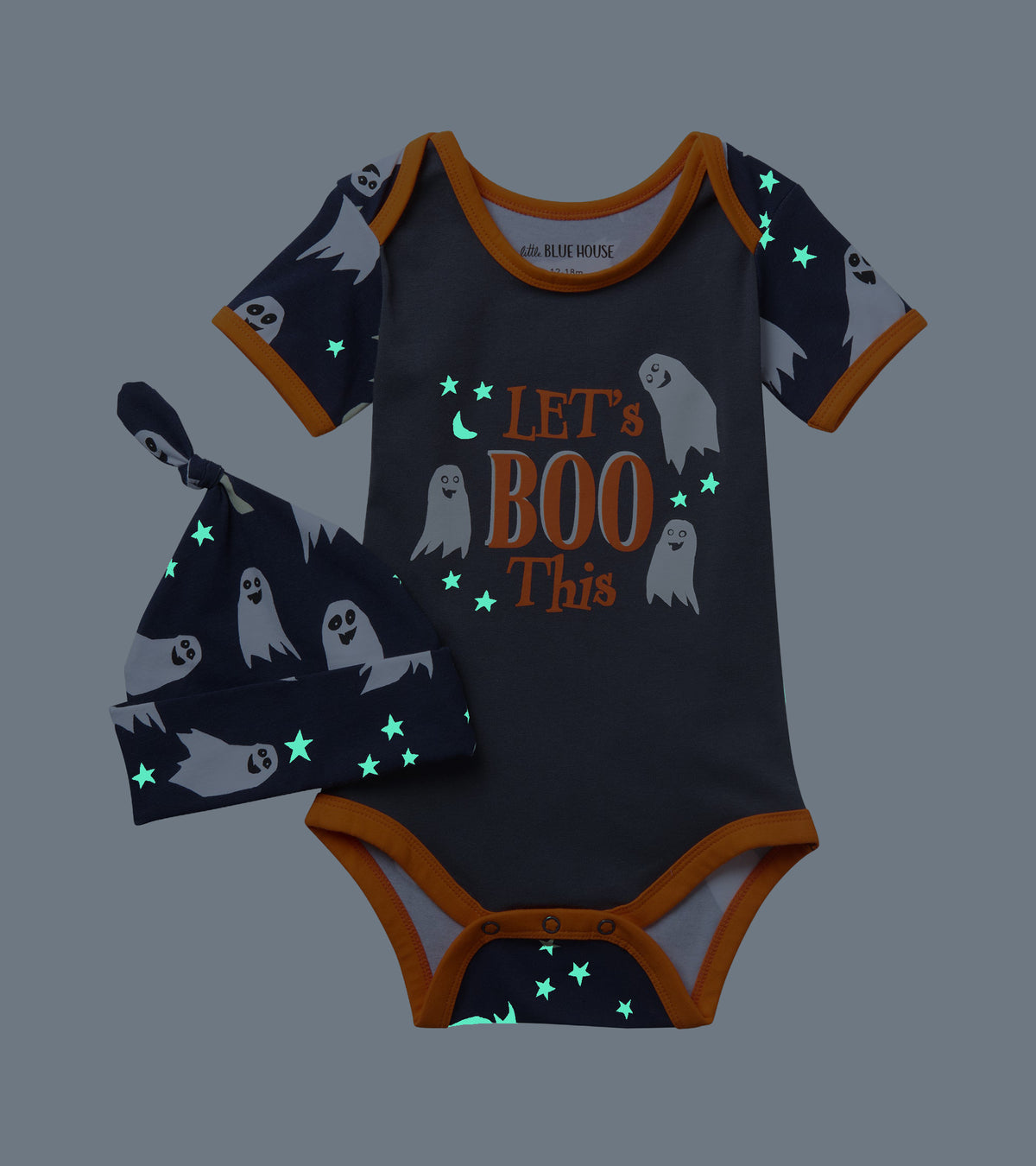 Baby ghost-print bodysuit and matching knot hat shown in the dark with glowing stars and moon details