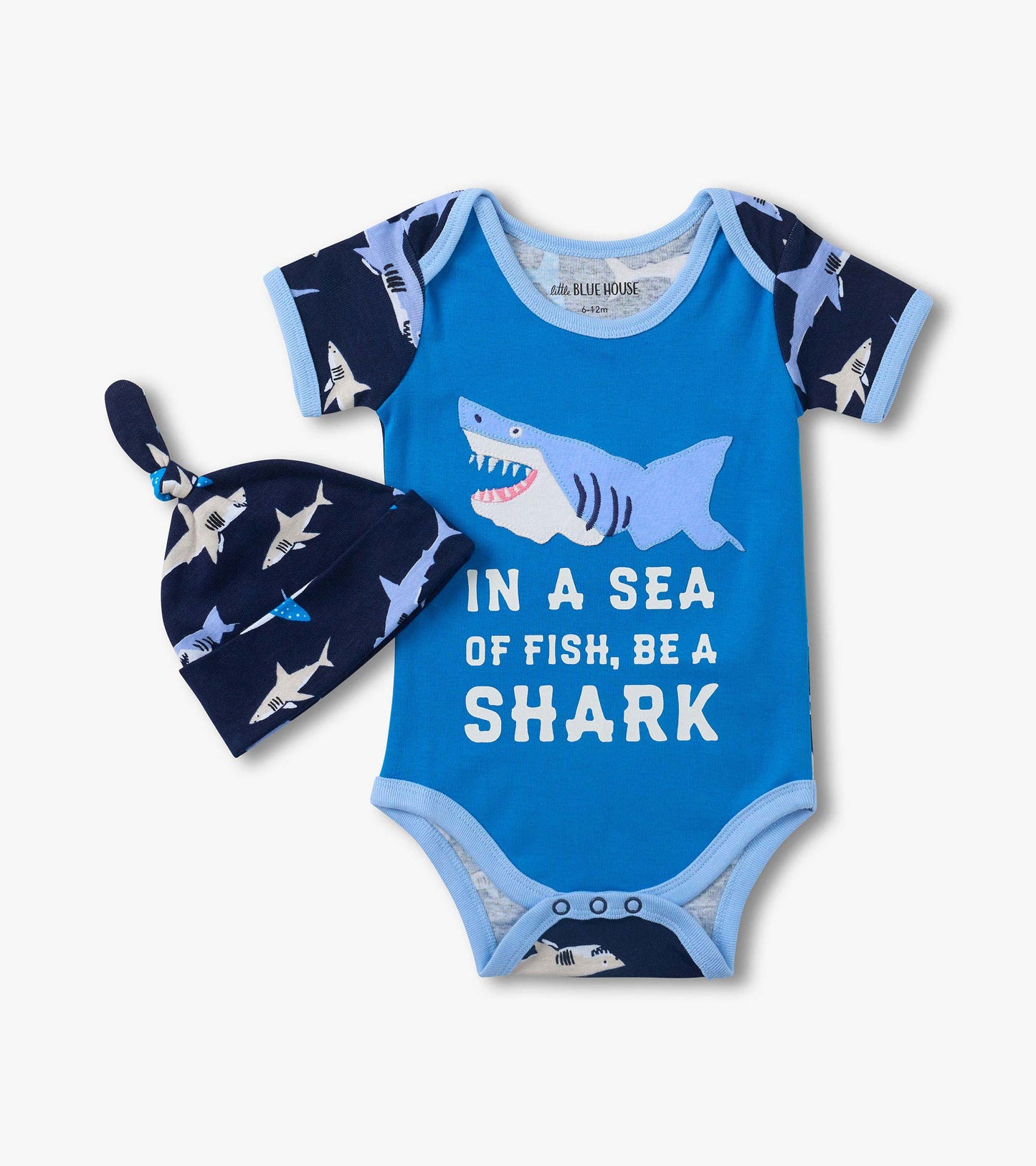 Blue baby bodysuit with shark graphic and text, paired with navy shark-print hat, front view