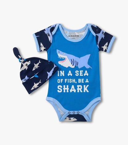 Blue baby bodysuit with shark graphic and text, paired with navy shark-print hat, front view