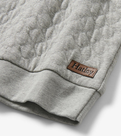 Close-up of grey quilted pullover hem with stitched Hatley logo patch