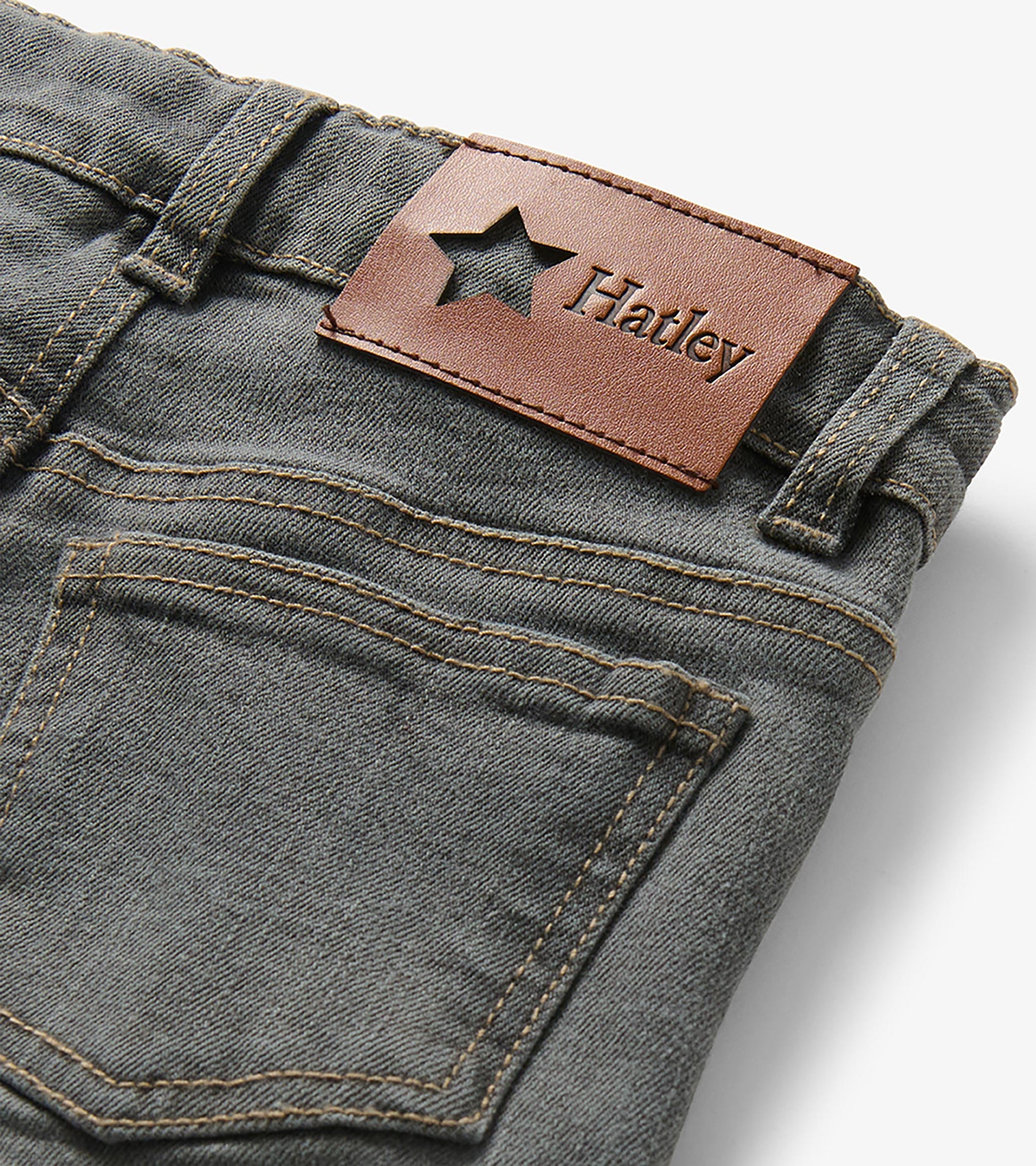 Close-up of the back waistband on charcoal grey jeans with brown Hatley logo patch and rear pocket