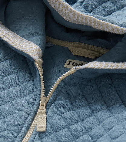 Close-up of faded blue quilted hoodie with cream zipper and braided trim inside the hood