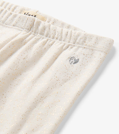 Close-up of cream glitter-speckled leggings with elastic waistband and small silver heart detail