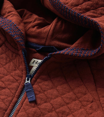 Close-up of madder brown quilted hoodie hood lining, blue zipper, and blue-and-brown trim detail
