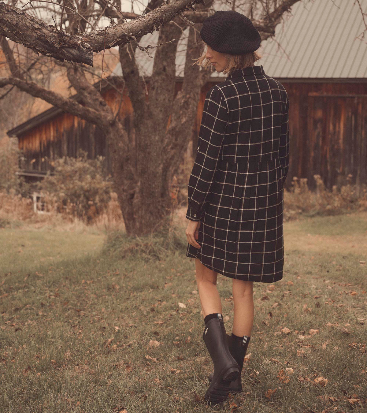Back view of black windowpane shirt dress on model, showing long sleeves and loose gathered back