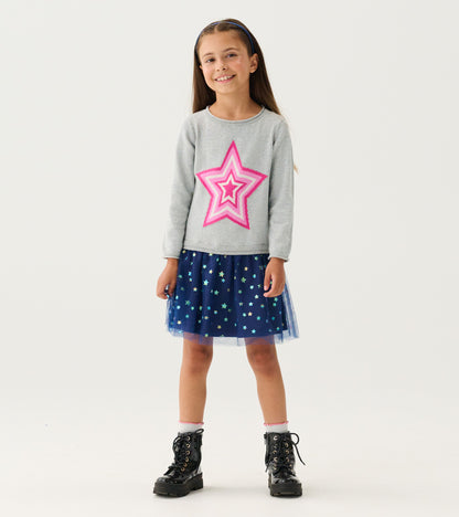 Girl wearing gray sweater dress with pink star and navy star-print tulle skirt, front view
