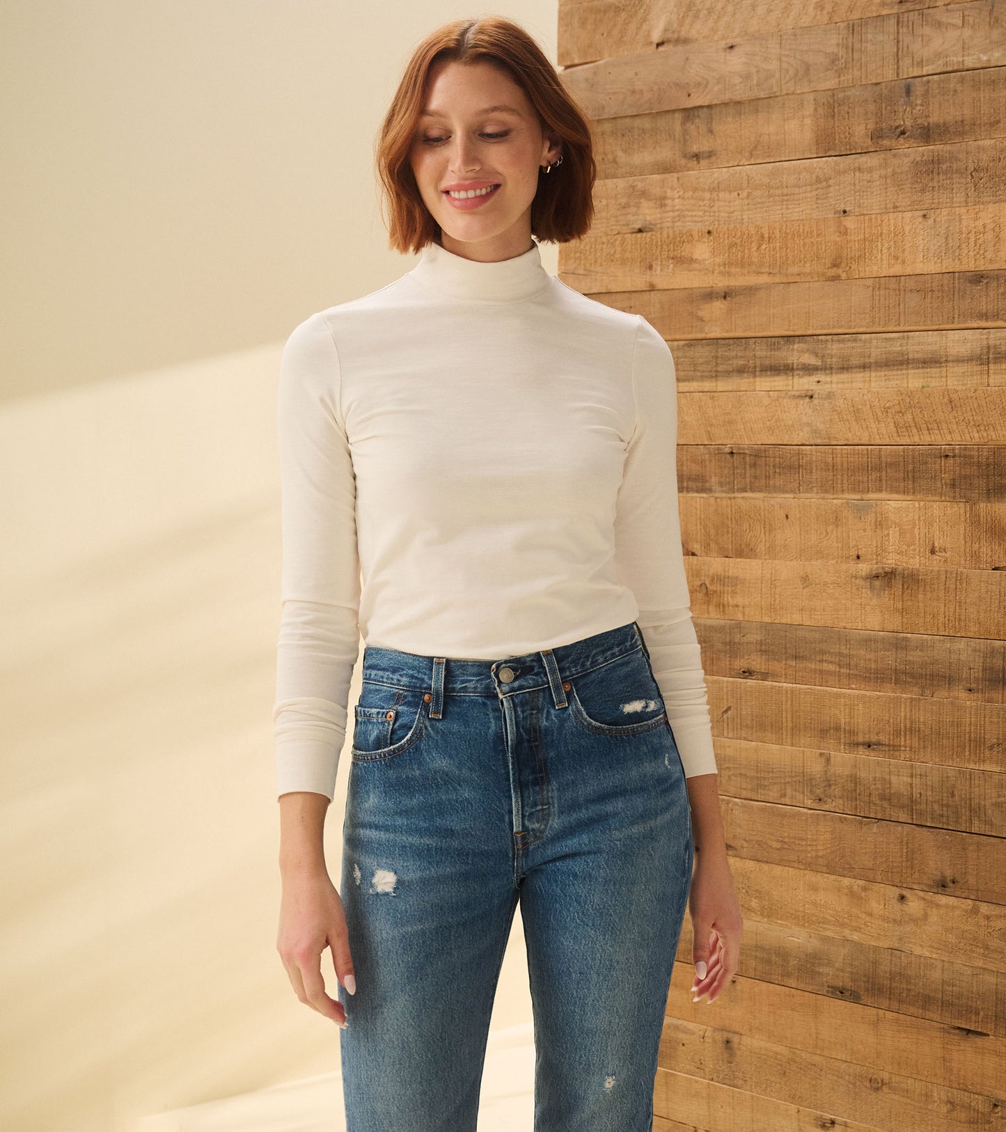 Model wearing cream white mock neck top with long sleeves, front view