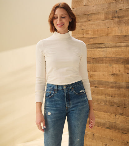 Model wearing cream white mock neck top with long sleeves, front view