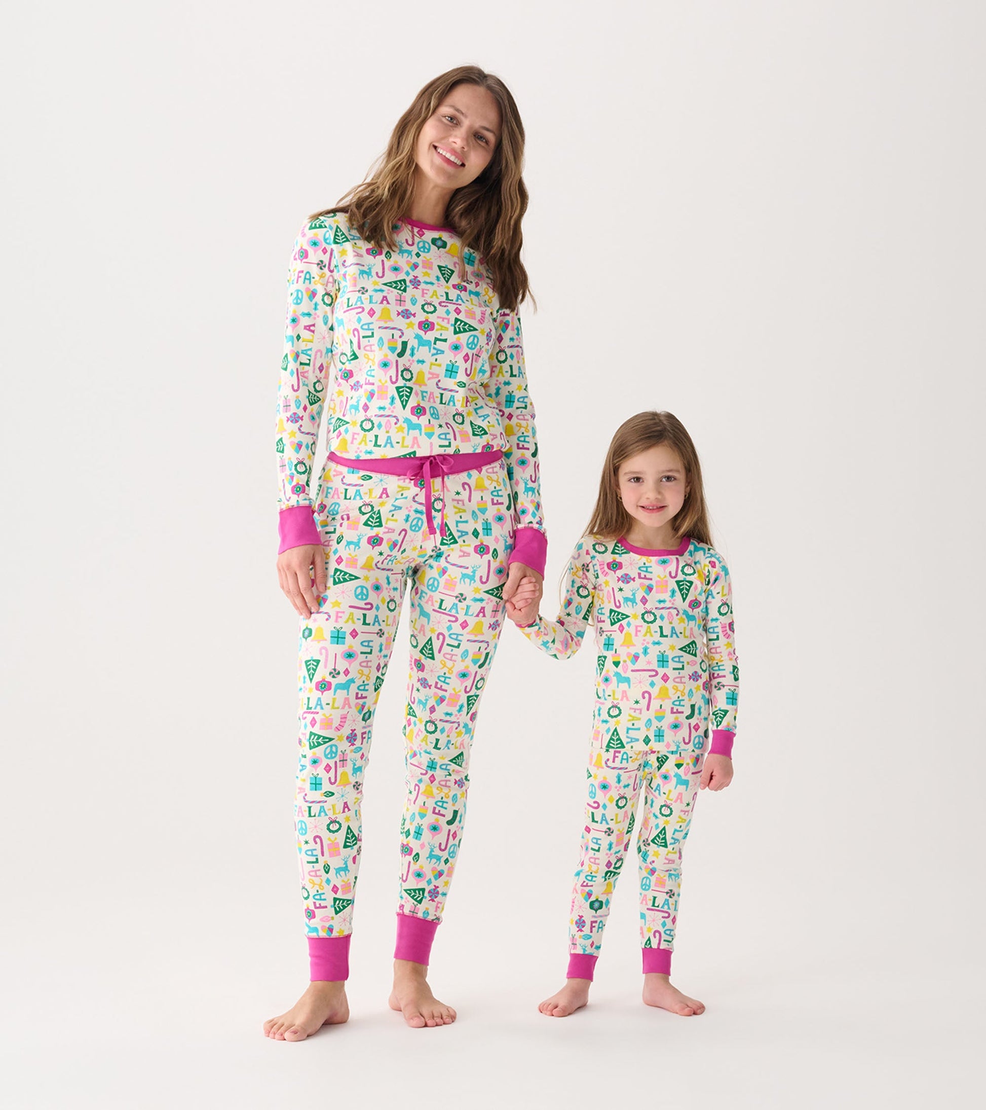 Women's and girl's matching pink pajama set with colorful holiday-themed patterns, featuring long sleeves and pants.