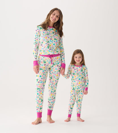 Women's and girl's matching pink pajama set with colorful holiday-themed patterns, featuring long sleeves and pants.