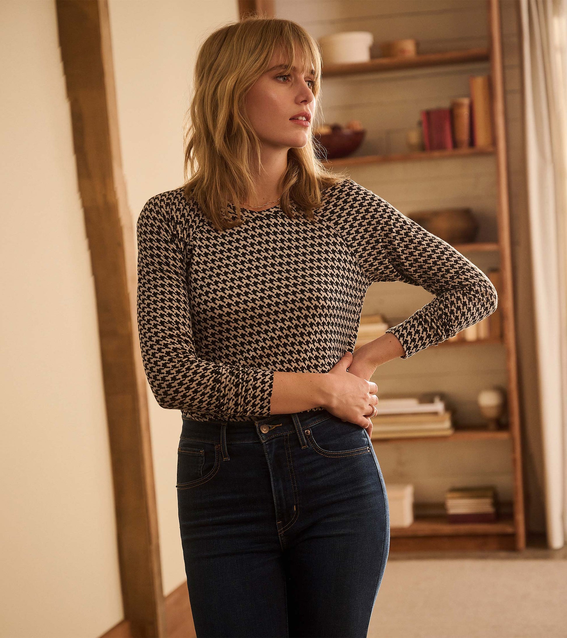 Three-quarter view of Chantel pullover in black and cream houndstooth, tucked into dark jeans