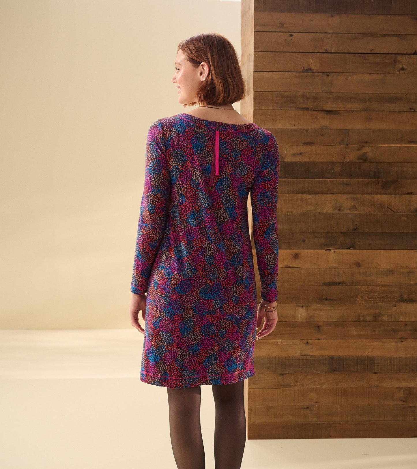 Back view of a long-sleeve dress with multicolor dot cluster print and a back keyhole detail