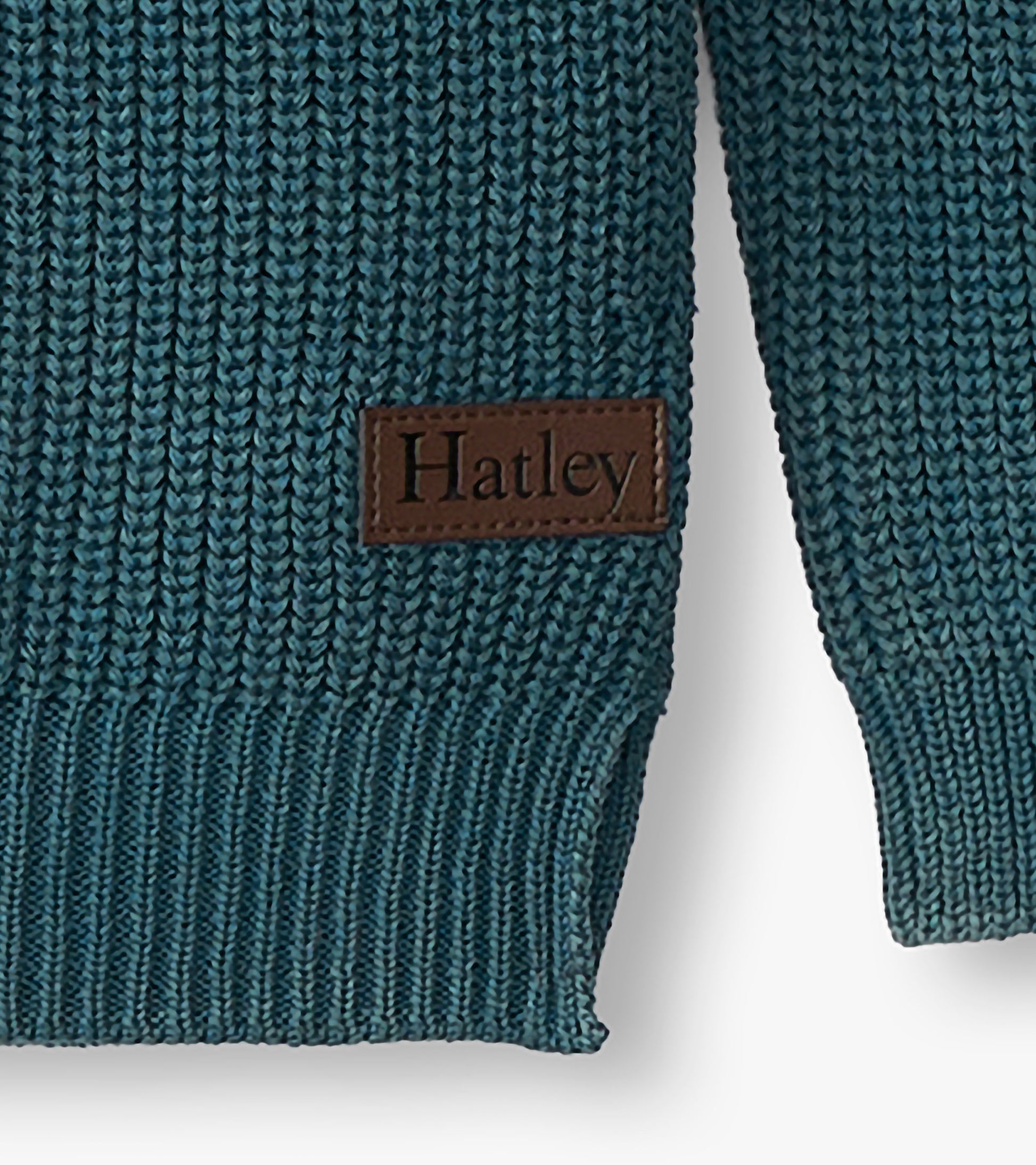 Close-up of blue knit sweater hem and sleeve with visible Hatley logo patch