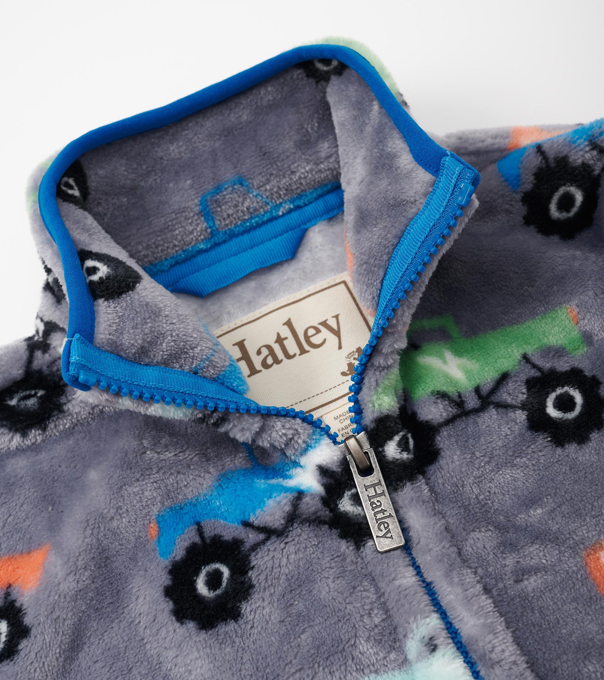 Gray fleece zip-up jacket featuring colorful monster truck patterns and a blue zippered collar.