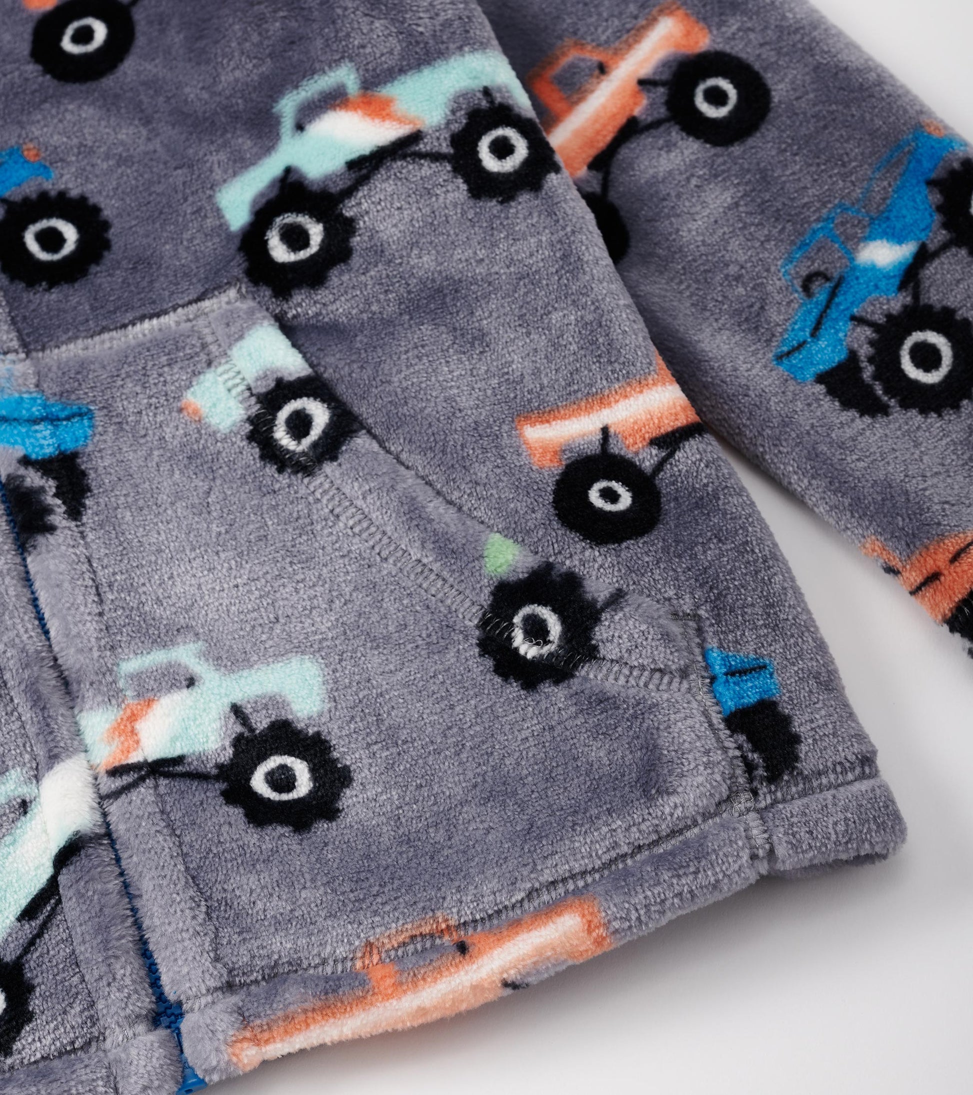 Gray fuzzy fleece zip-up jacket featuring colorful monster truck patterns and front pockets.