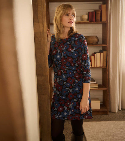 Long-sleeve black dress with red and blue floral pattern, worn with black tights and boots, front view