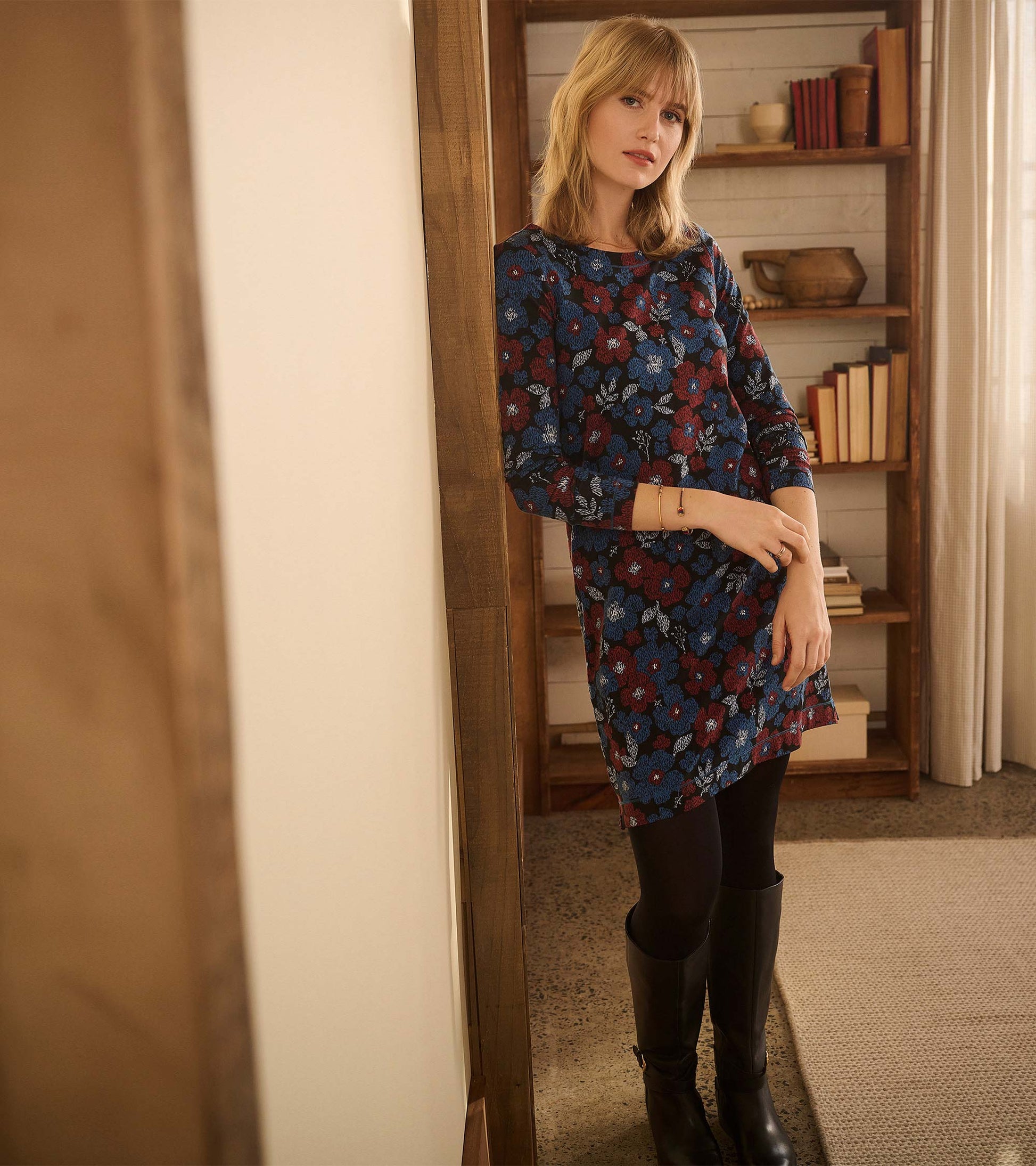 Long-sleeve navy dress with red and blue floral print, worn with black tights and boots, front view