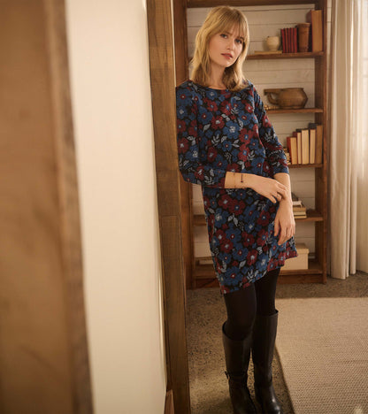 Long-sleeve navy dress with red and blue floral print, worn with black tights and boots, front view