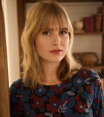 Front view of a black dress with red, blue, and white textured floral print and round neckline