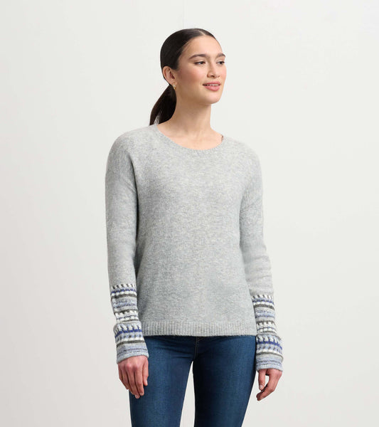 Grey melange sweater featuring jacquard patterned cuffs and a classic crew neckline, styled with fitted jeans.
