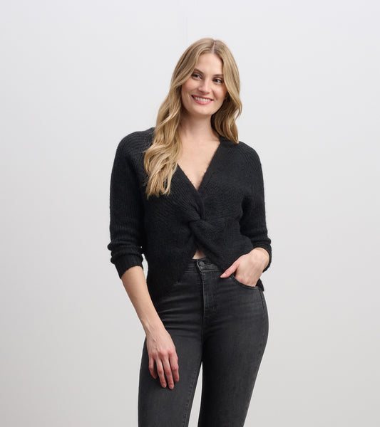 Black crossover sweater with a knotted front, featuring long sleeves and a relaxed fit, styled with dark jeans.