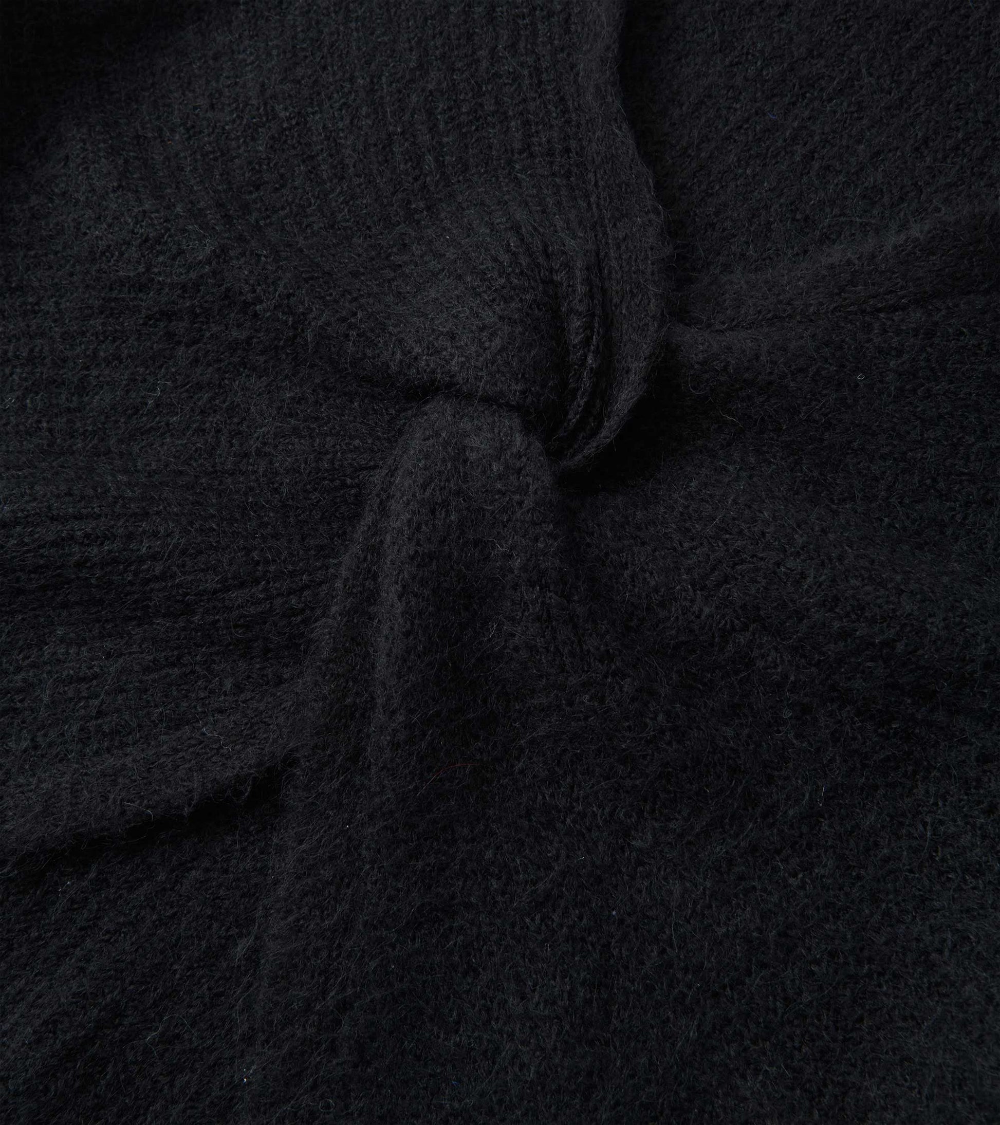 Black cross over sweater made of soft, textured fabric, showcasing a cozy and relaxed design.
