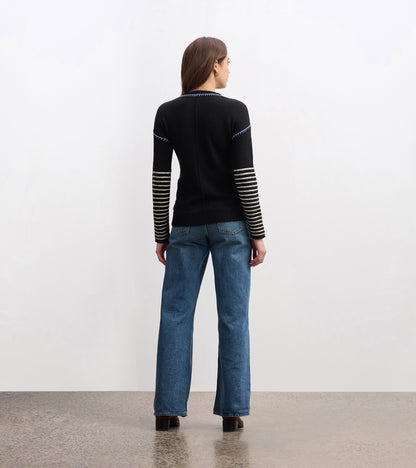 Black sweater with striped sleeves, fitted shape, and a round neckline, worn with blue jeans, viewed from the back.