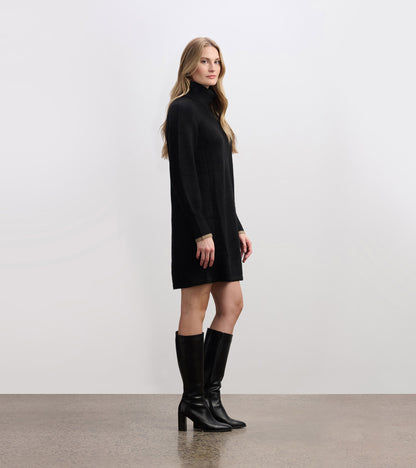 Black swing sweater dress with a high collar and long sleeves, styled with knee-high black boots.