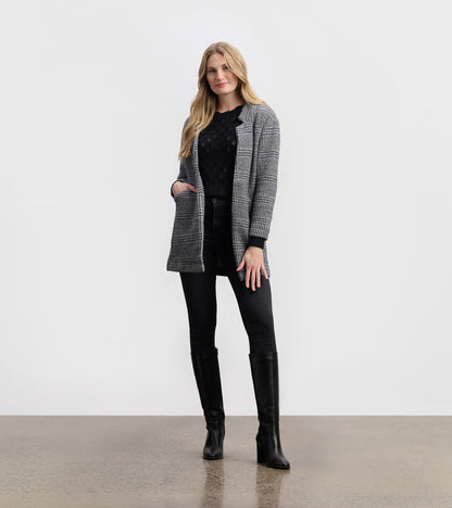 Black check open blazer with a relaxed fit, featuring pockets and a stylish collar, paired with black jeans and boots.