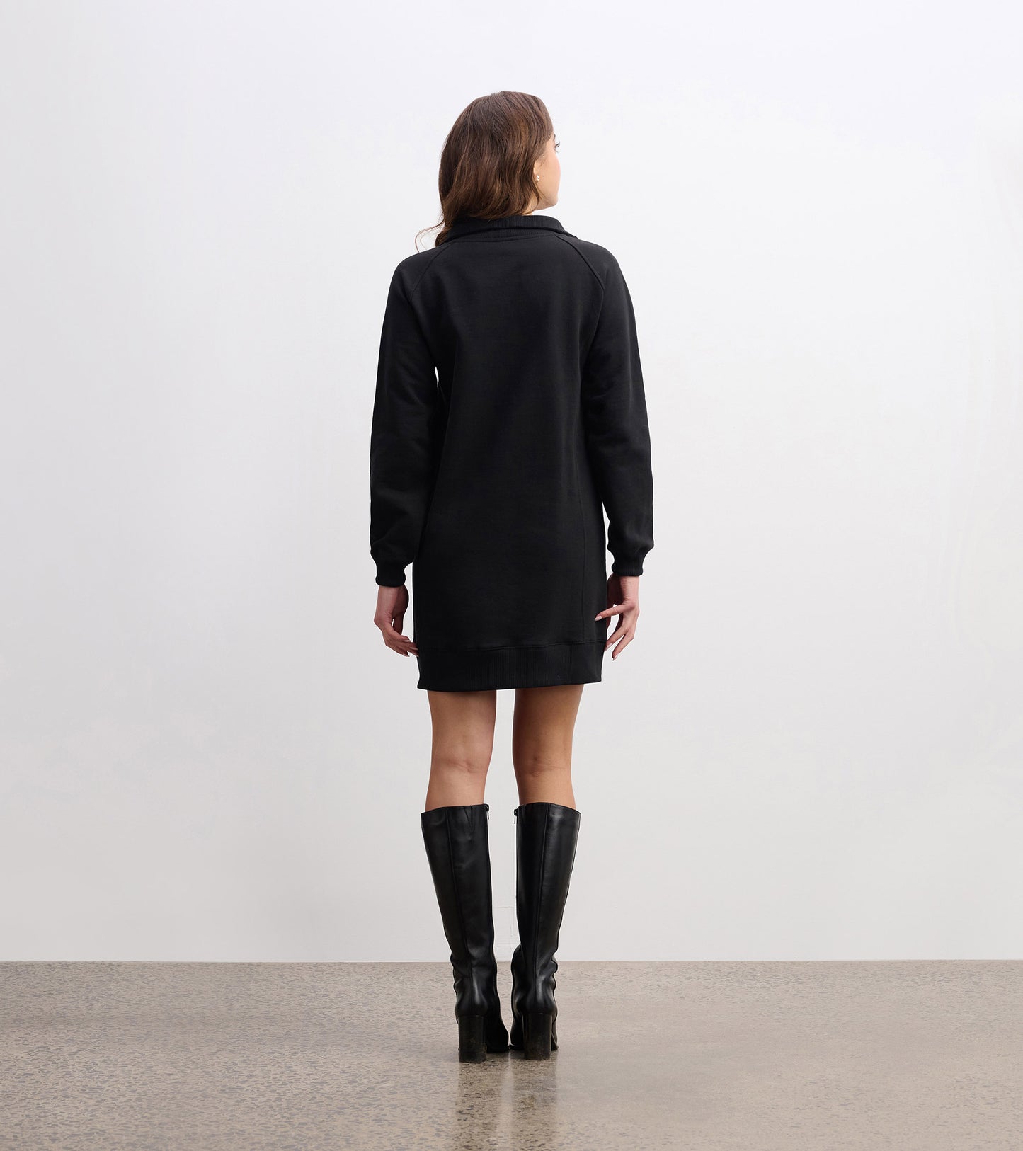 Black notch neck dress with long sleeves, featuring a relaxed fit and reaching mid-thigh, styled with knee-high boots.