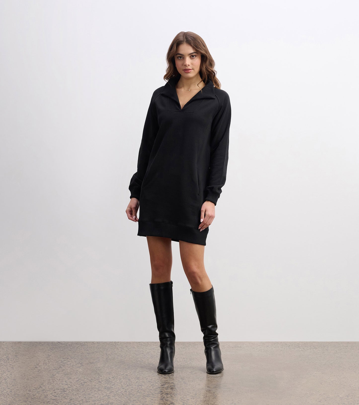 Black notch neck dress with long sleeves, relaxed fit, and a casual style, paired with knee-high black boots.