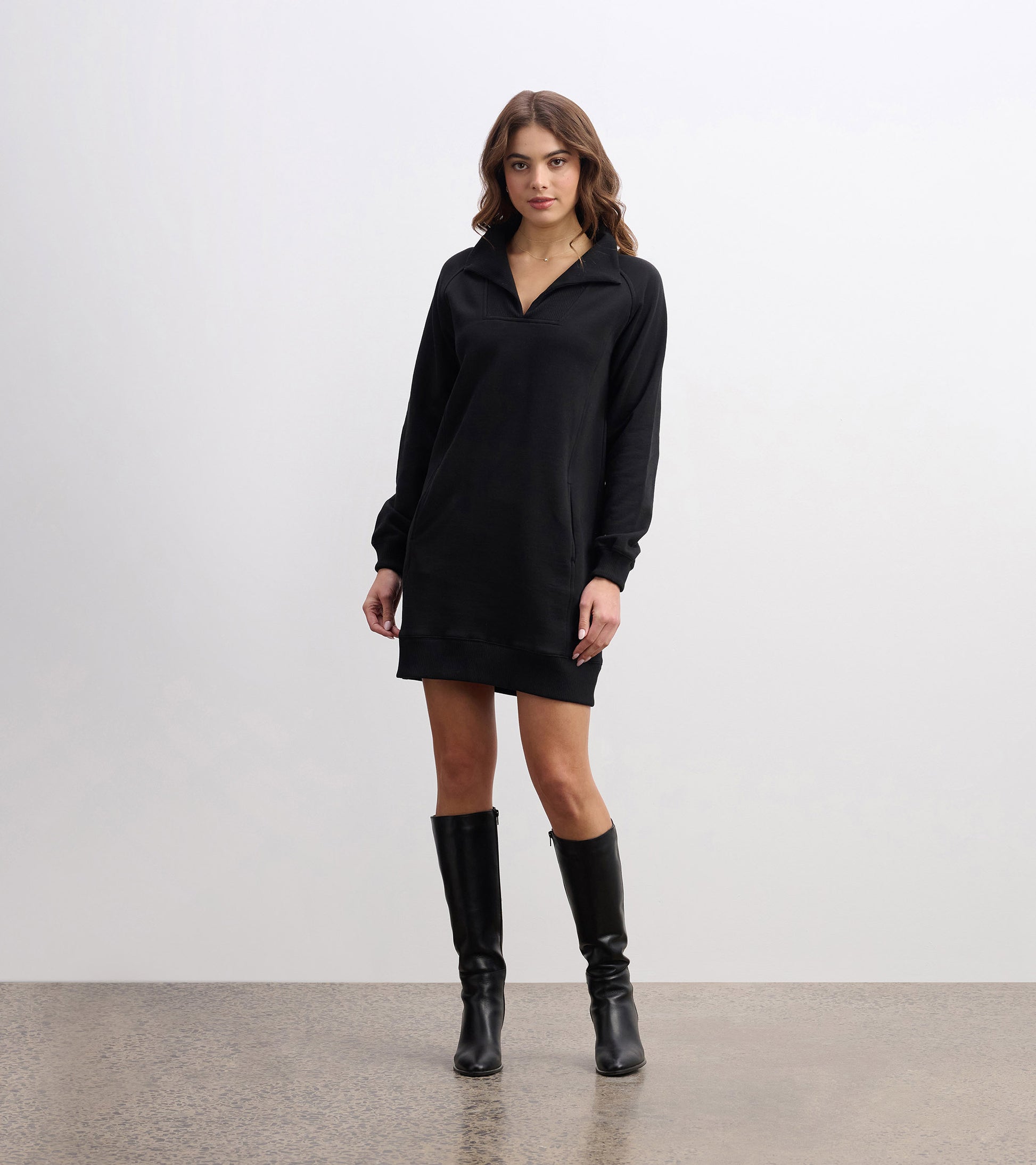 Black notch neck dress with long sleeves, relaxed fit, and a casual style, paired with knee-high black boots.